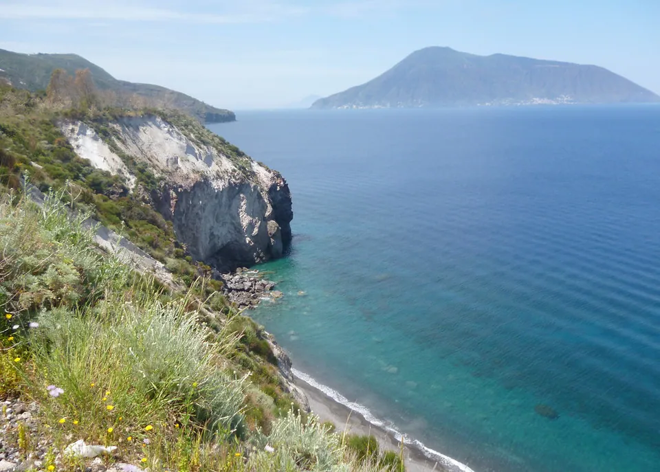 Ljus, brant kust på Lipari med Salina i bakgrunden