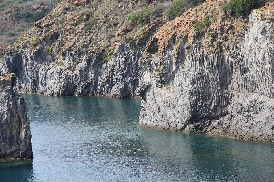 Klippväggar och vatten i Cala Junco på Panarea